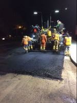 Street paver at night with workers 