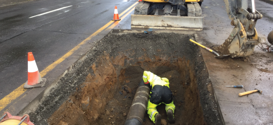 Exposed water main in sidewalk next to road