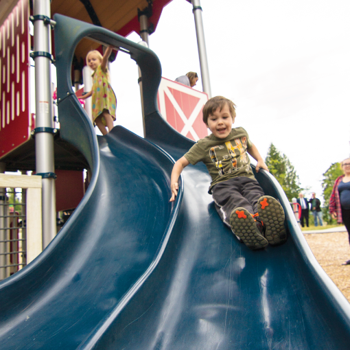Child going down playground slide at park